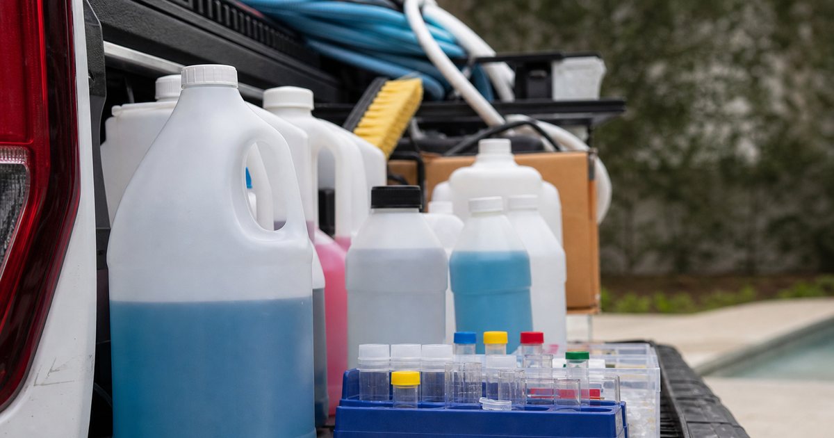Chemical jugs and testing supplies organized in the bed of a pool service truck
